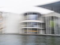 a blurry picture of a building from the water in a river area with one yellow umbrella