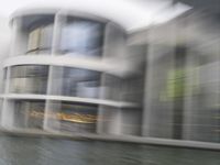 a blurry picture of a building from the water in a river area with one yellow umbrella