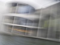 a blurry picture of a building from the water in a river area with one yellow umbrella