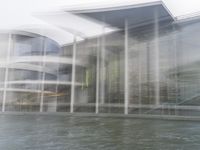 a blurry picture of a building from the water in a river area with one yellow umbrella