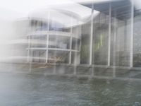 a blurry picture of a building from the water in a river area with one yellow umbrella