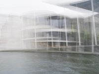 a blurry picture of a building from the water in a river area with one yellow umbrella