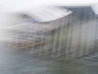 a blurry picture of a building from the water in a river area with one yellow umbrella