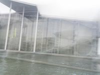 a blurry picture of a building from the water in a river area with one yellow umbrella