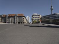 an empty street with tall buildings and a man walking through it, as another person on a skateboard rides away