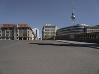 an empty street with tall buildings and a man walking through it, as another person on a skateboard rides away