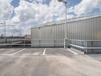 a parking lot with a metal fence and a long pole in the middle of it