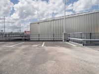 a parking lot with a metal fence and a long pole in the middle of it