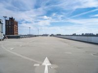 an empty parking lot is seen with two arrows on it's side and a building in the background