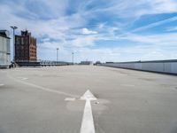 an empty parking lot is seen with two arrows on it's side and a building in the background