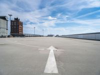 an empty parking lot is seen with two arrows on it's side and a building in the background