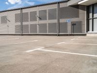 a parking space with a fence in front of it with no one outside the building