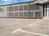 a parking space with a fence in front of it with no one outside the building