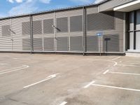 a parking space with a fence in front of it with no one outside the building