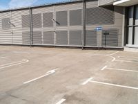 a parking space with a fence in front of it with no one outside the building