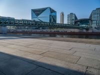 a skateboarder riding on a cement ramp next to a city street under a bridge