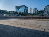 a skateboarder riding on a cement ramp next to a city street under a bridge