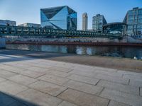 a skateboarder riding on a cement ramp next to a city street under a bridge