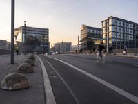 several concrete ball sitting on the side of a street near buildings on a clear day