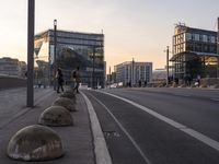 several concrete ball sitting on the side of a street near buildings on a clear day