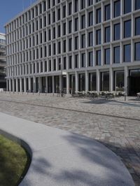 a brick building with glass windows and sidewalk leading to it and a black fire hydrant