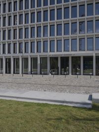 a brick building with glass windows and sidewalk leading to it and a black fire hydrant