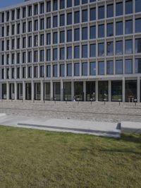 a brick building with glass windows and sidewalk leading to it and a black fire hydrant