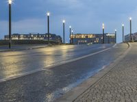 a walkway with two benches and several street lights at dusk on top of it in the city