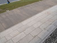 a boy rides a skateboard down a sidewalk near a water feature in the background