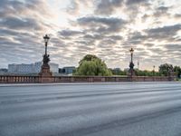 a view of a city street from across a bridge during the evening with cloudy skies