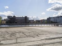 a cement parking lot with many buildings in the background and train tracks on a street