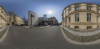 a 360 - view photo showing buildings at a street corner and some pedestrians, looking back