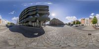 a fish eye photo of a street outside of a building and parking lot with many cars in front of it