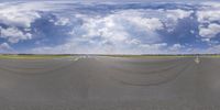 a mirror image shows a wide angle shot of a runway surrounded by cloud filled sky