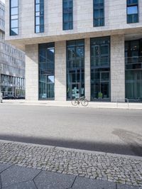 there is a woman standing in the street in front of a building that has glass on it