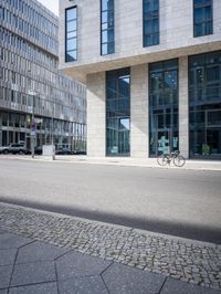 there is a woman standing in the street in front of a building that has glass on it