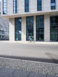 there is a woman standing in the street in front of a building that has glass on it