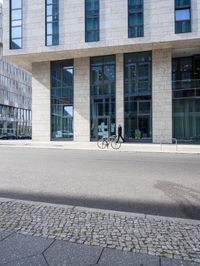 there is a woman standing in the street in front of a building that has glass on it