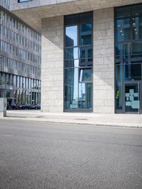 there is a woman standing in the street in front of a building that has glass on it