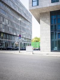 there is a woman standing in the street in front of a building that has glass on it