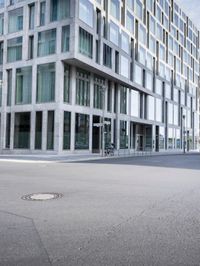 there is a woman standing in the street in front of a building that has glass on it