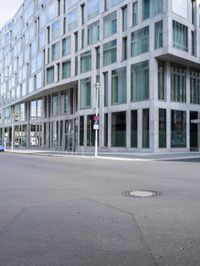 there is a woman standing in the street in front of a building that has glass on it