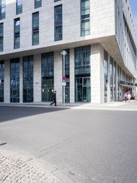 there is a woman standing in the street in front of a building that has glass on it