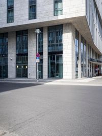 there is a woman standing in the street in front of a building that has glass on it