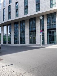 there is a woman standing in the street in front of a building that has glass on it