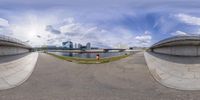 a fish eye lens of some people in the park near a river bank and some buildings