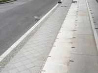 a paved road in the middle of the day with cars parked on both sides of the street