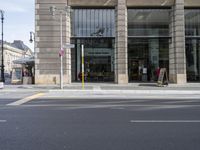 a man is walking on the road outside of the building with people sitting at tables