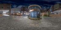 a photo taken through a fisheye lens of buildings at night or day with one building