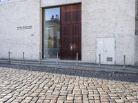 a cobblestone street is near a large old building on a sunny day in the country